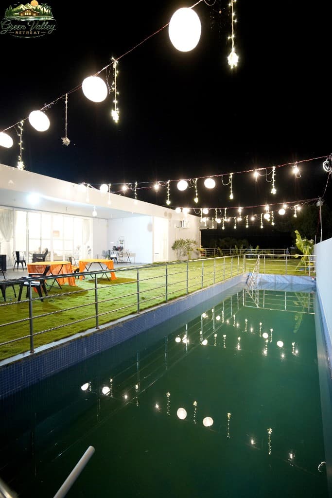 Swimming pool with festive string lights at Green Valley Retreat
